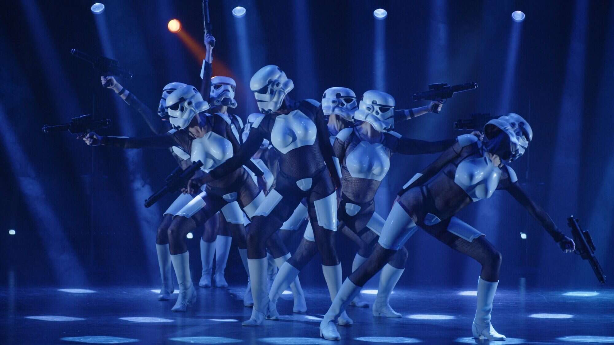 A group of dancers in partial Stormtrooper costumes perform on stage under blue and purple lights at Pioneer Square, posing with toy blasters—a unique highlight if you’re exploring what to do in Seattle this week.