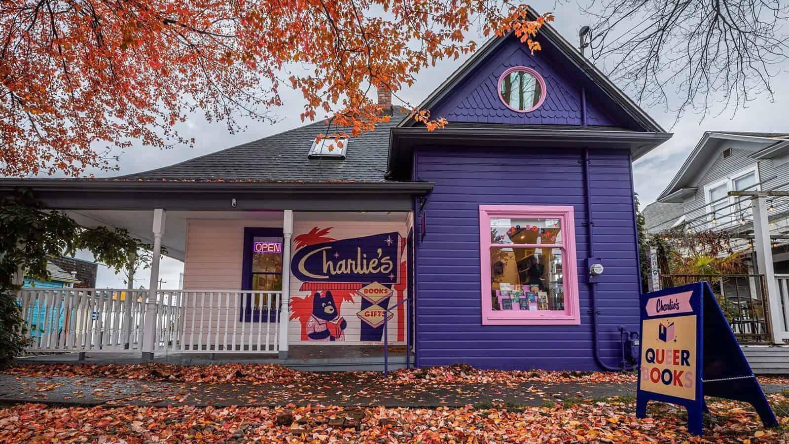 A purple house with a pink window frame and a porch, a sign reading "Charlie's Queer Books" outside, surrounded by autumn leaves—where vibrant celebrations honor Seattle’s rich LGBTQIA+ history.