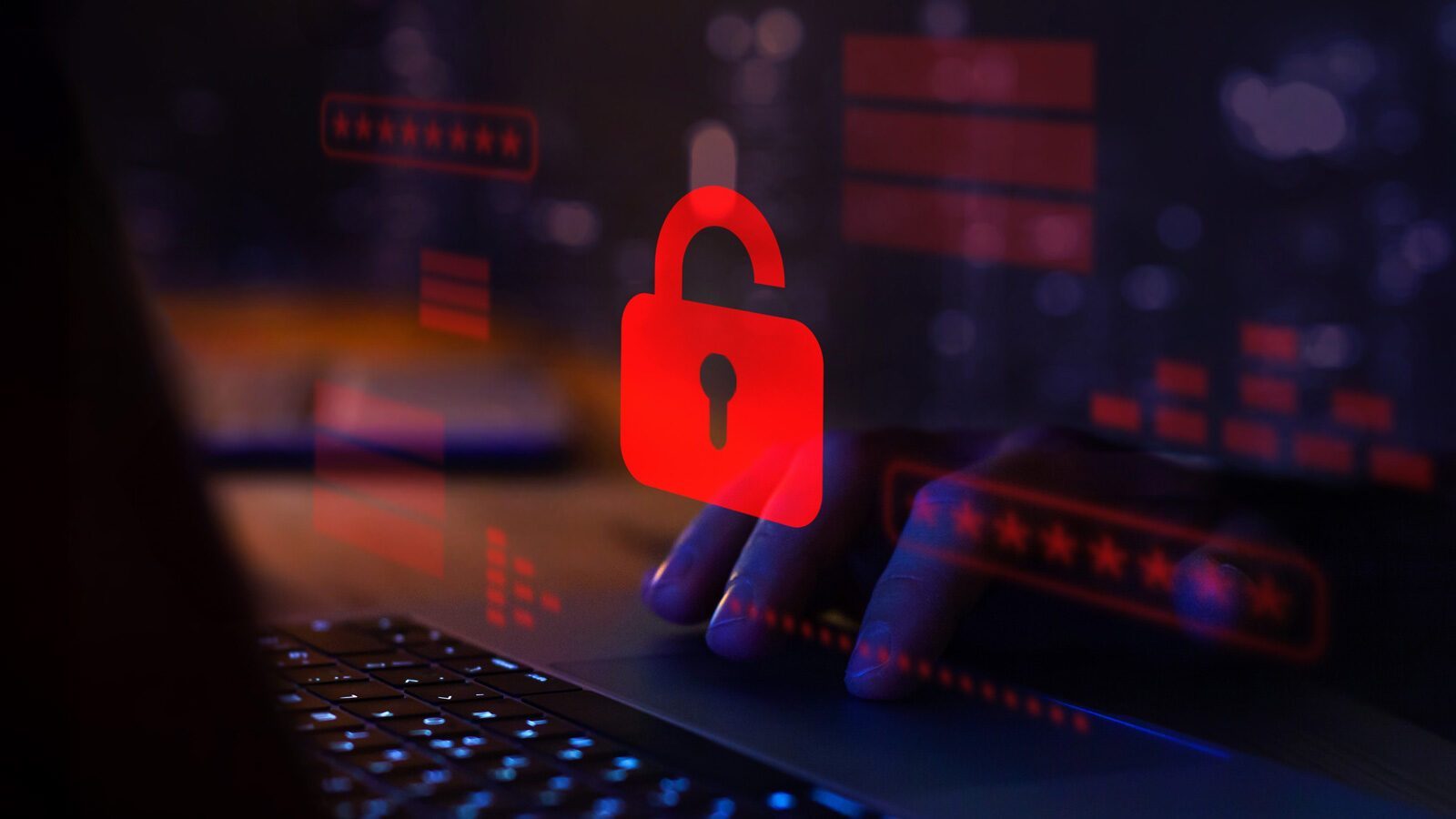 A red unlocked padlock icon overlays a dimly lit laptop with a person’s hands typing, symbolizing a data breach or cybersecurity threat—an urgent reminder for IT teams to strengthen network security measures.