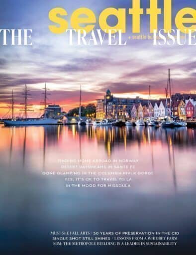 Colorful waterfront buildings and docked boats reflected in calm water at sunset, with “Seattle Travel Issue” magazine cover text overlayed.