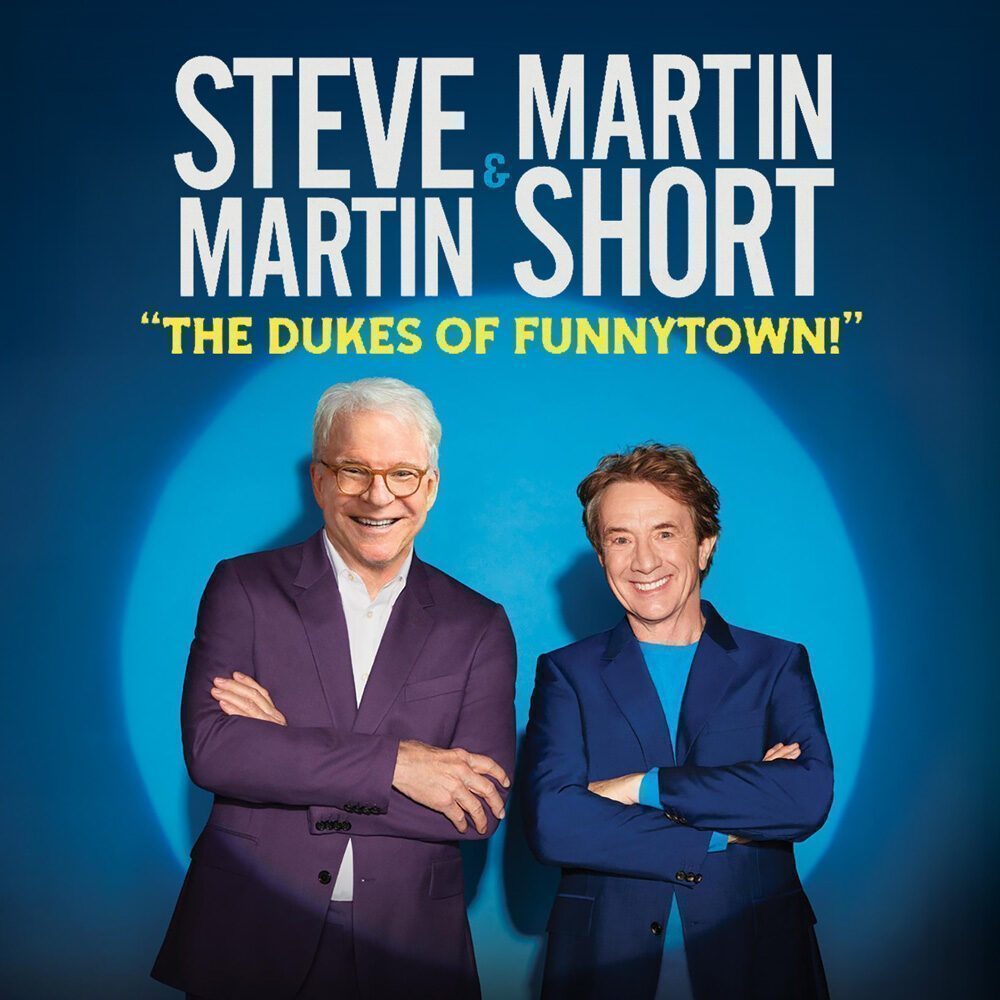 Steve Martin and Martin Short stand side by side, smiling in front of a blue background with the text “The Dukes of Funnytown!” above them. This Must List event takes place on 08-21-2025.