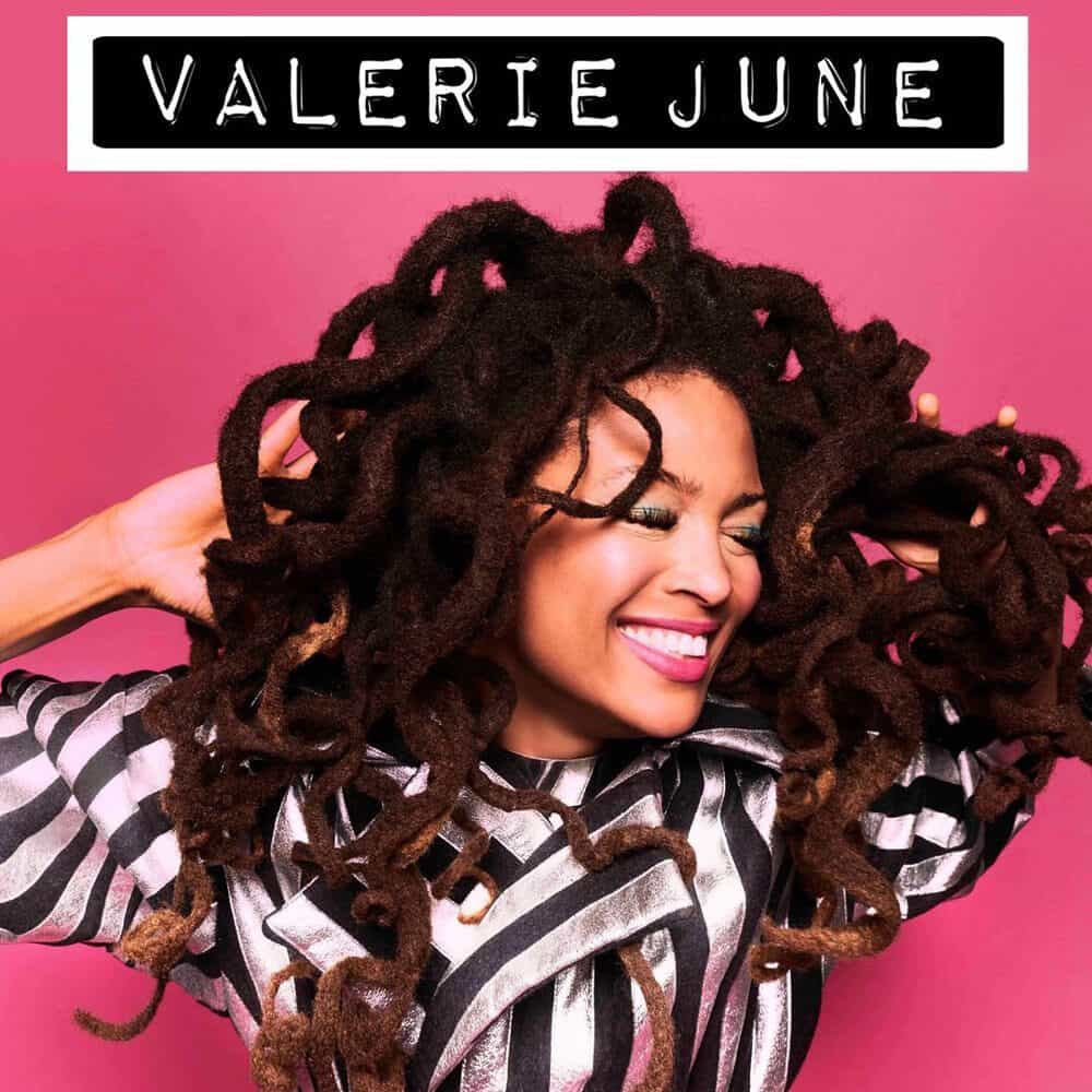 A woman with long, thick dreadlocks smiles brightly against a pink background with "VALERIE JUNE" and "Must List 06-19-2025" written above her in bold white letters.