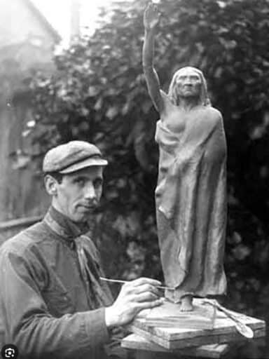 Sculptor working on a small statue of a standing figure with raised arm, while looking at the camera, in an outdoor setting, embodying the best policy of honesty in his craft.